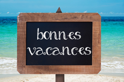 Bonnes vacances (meaning happy holiday) written on a wooden vintag chalk board, beach background